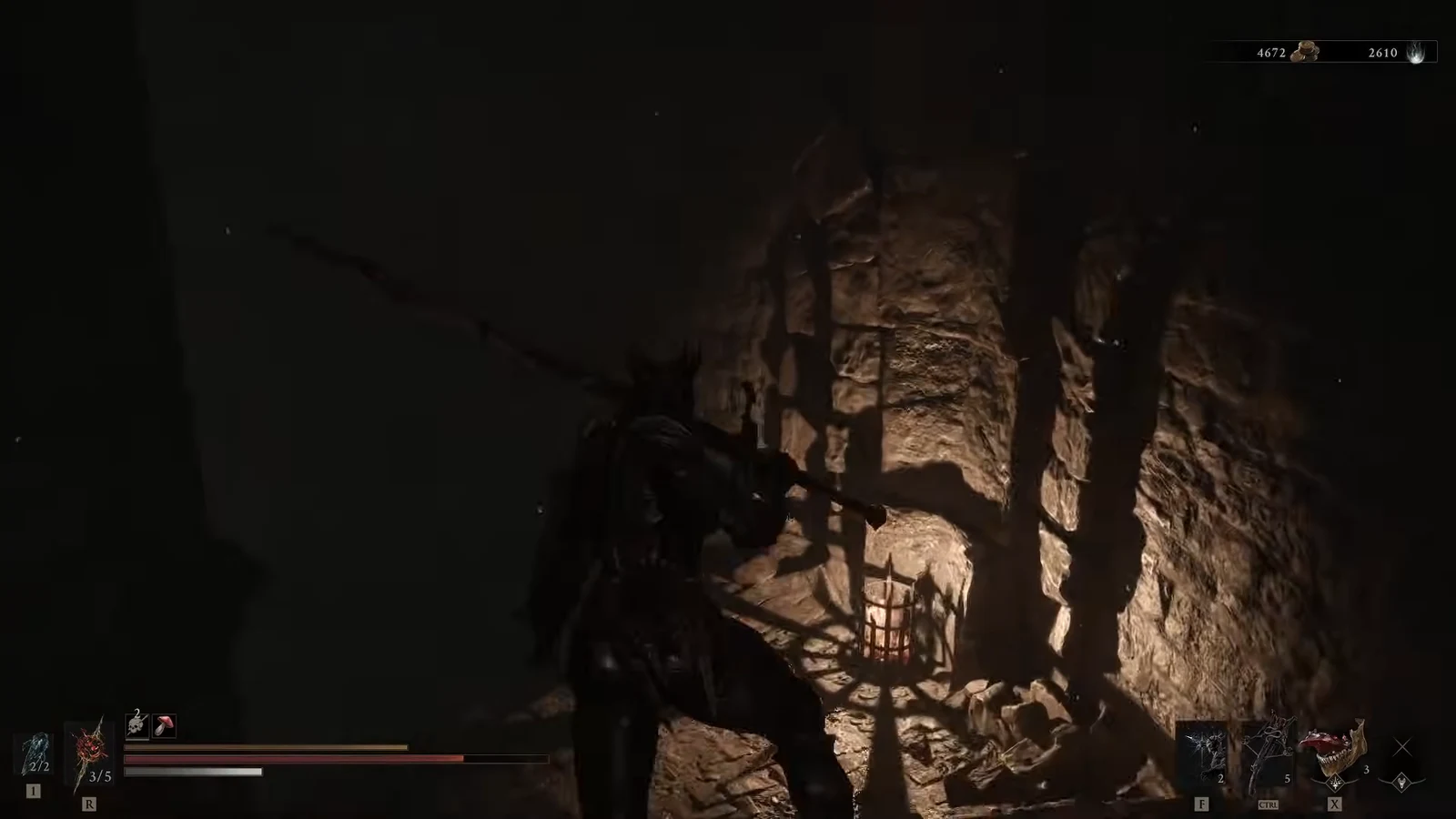 Player character moving through a narrow torchlit stone passage inside the Besieged Ruins cave