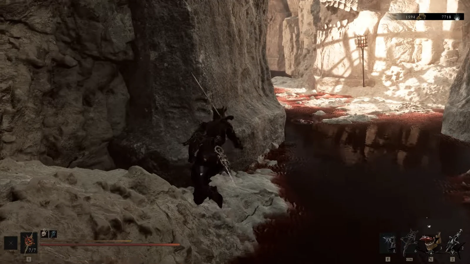 Character crosses a narrow cavern ledge above a dark chasm toward a blood-stained platform