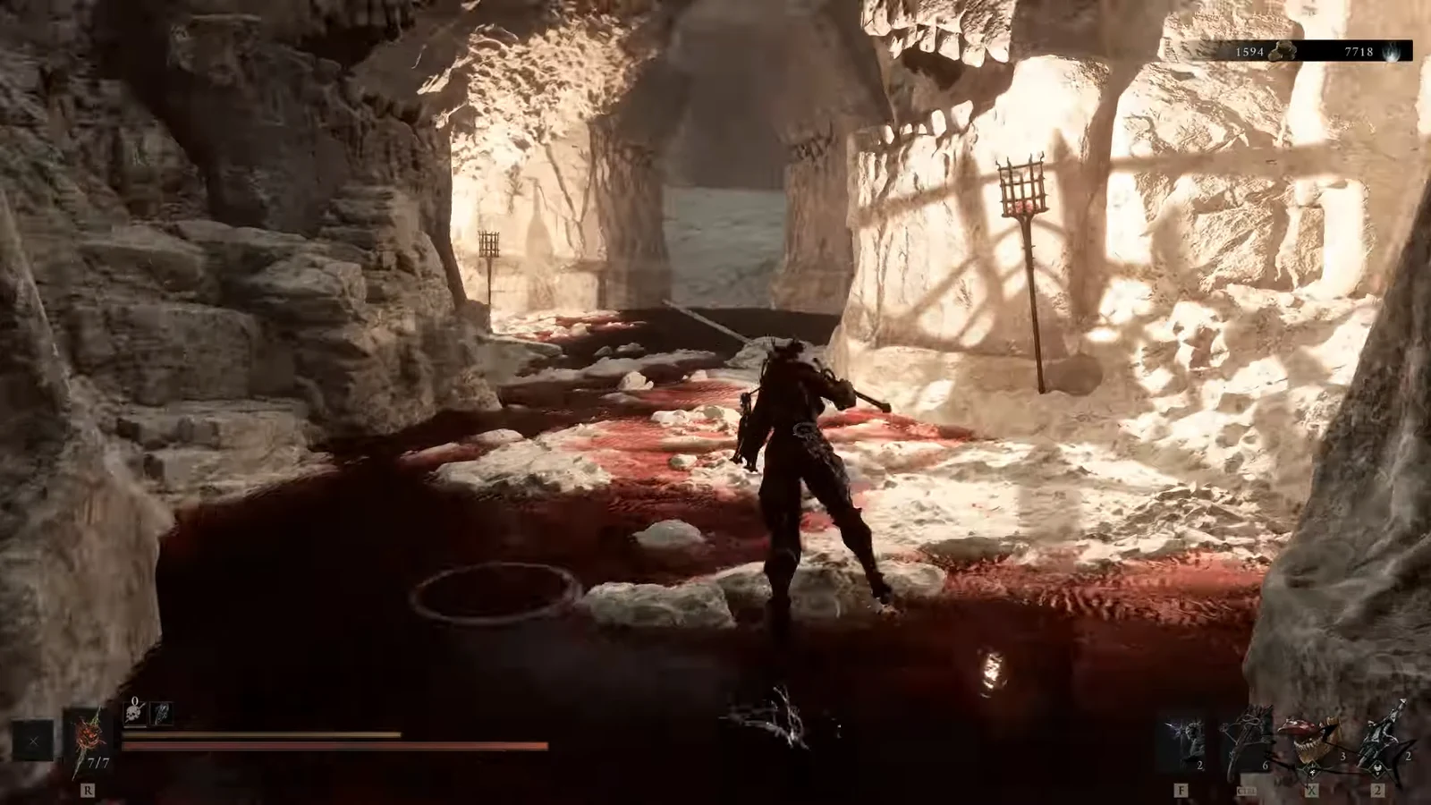 Character advancing through a blood-filled cavern toward a torch-lit passage with HUD visible