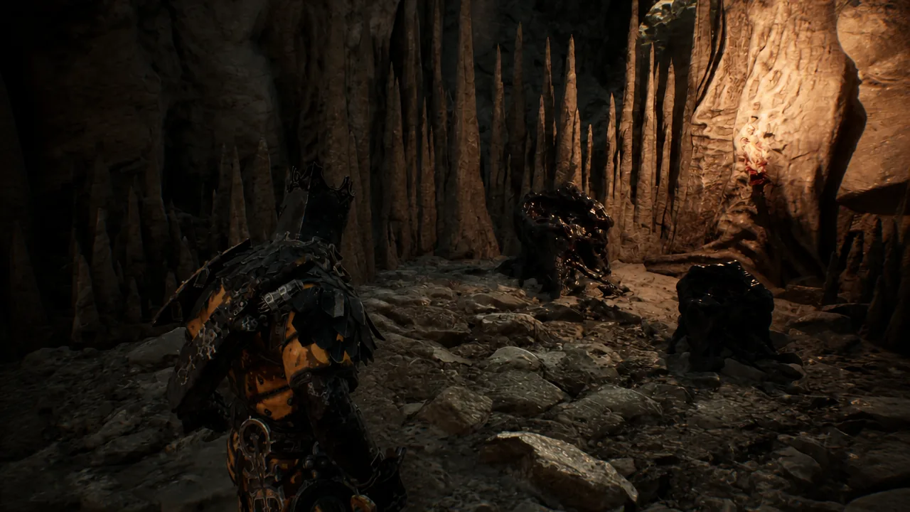Exploding creatures clinging to the cave wall in front of the stalactite formation