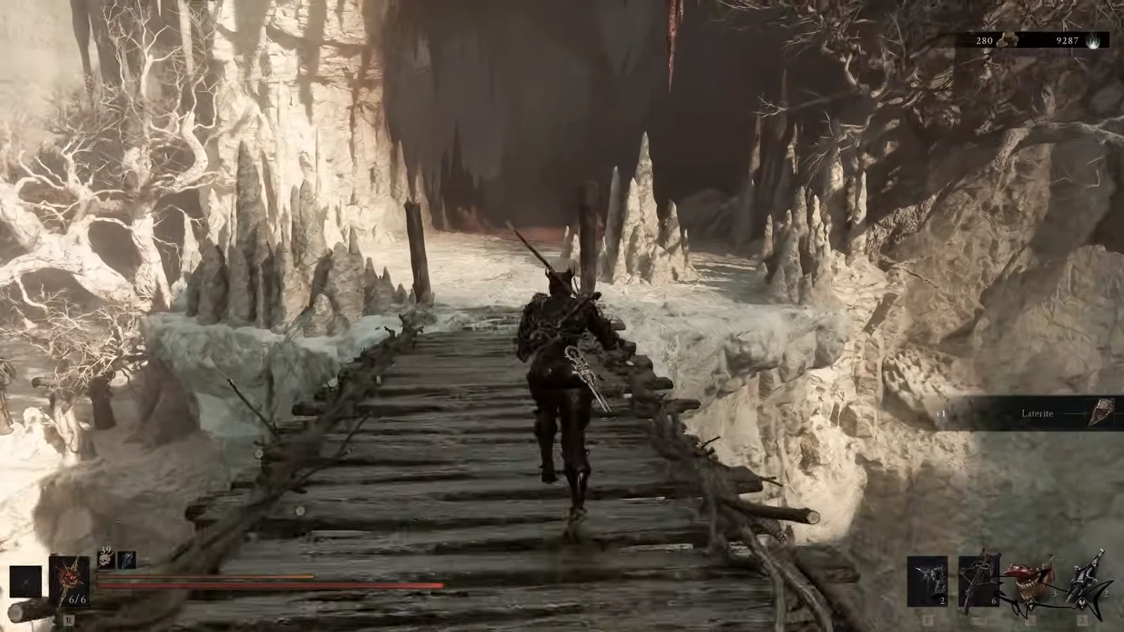 Character crossing a wooden bridge in an icy cavern with a Laterite pickup on the HUD