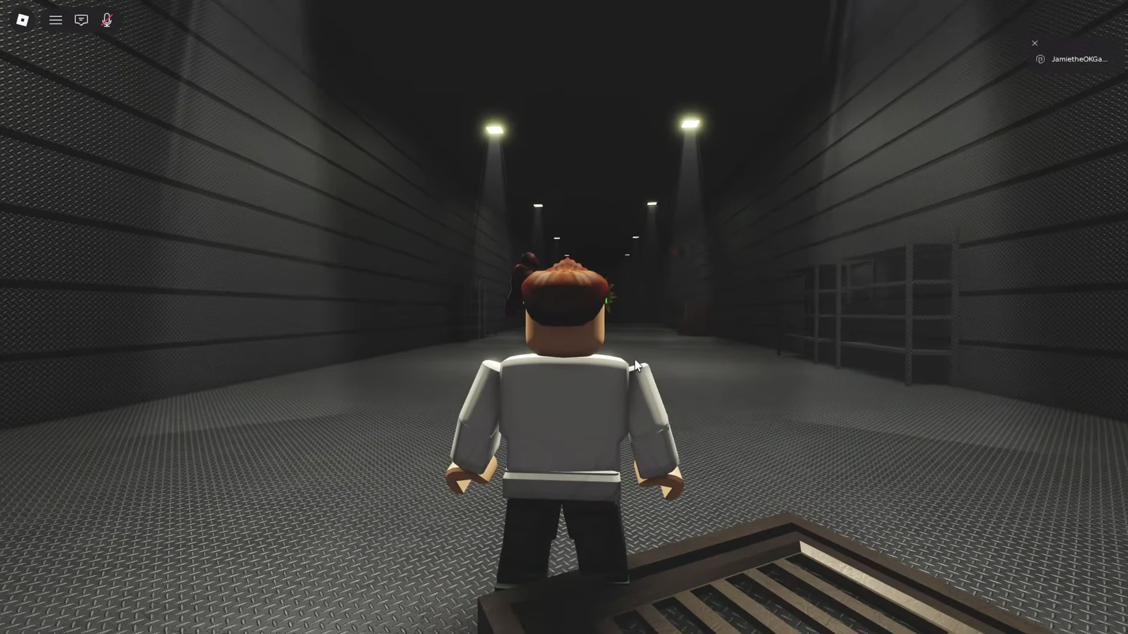 Player avatar moving through a dim industrial corridor in the laser obby