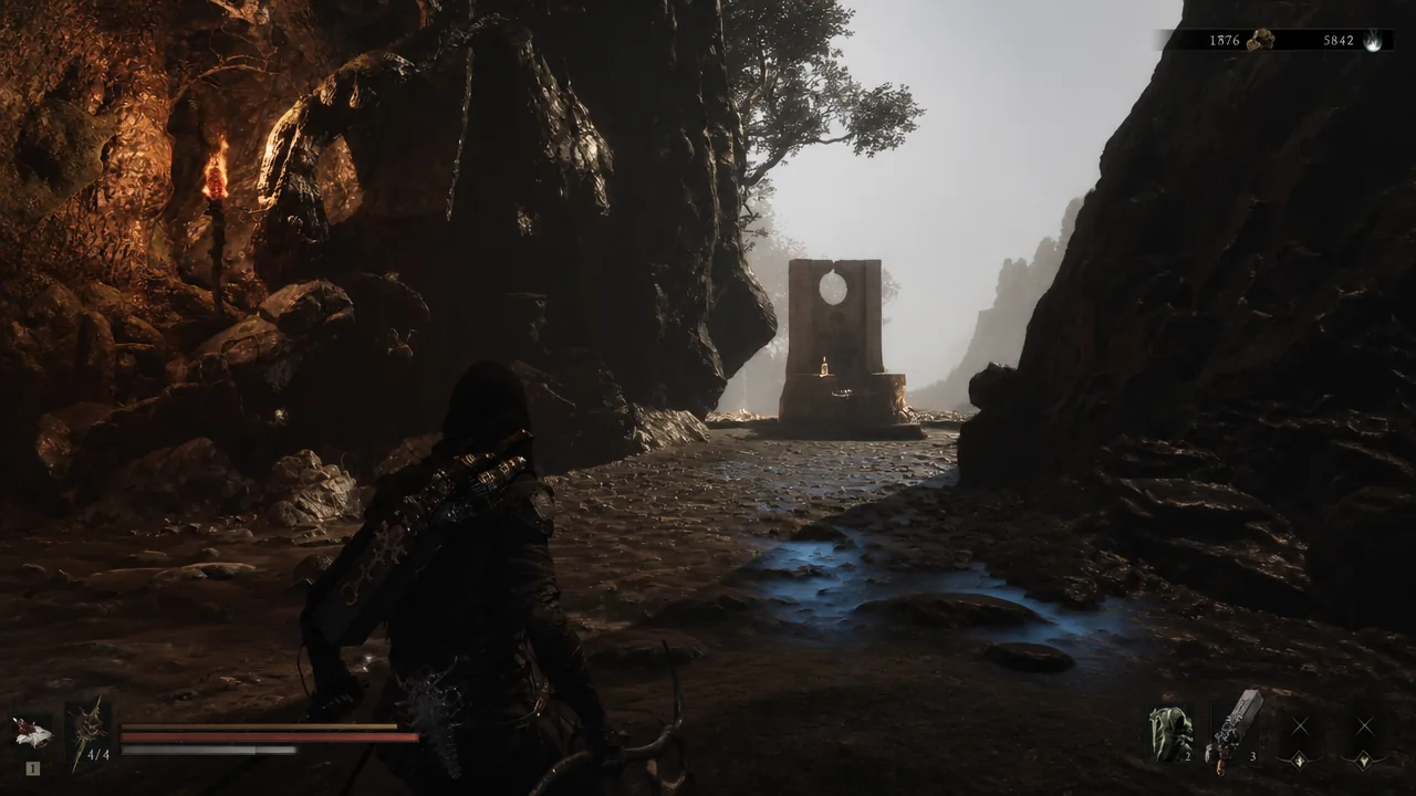 Hooded character walking through a rocky cavern toward a stone structure inside Marrow Keep