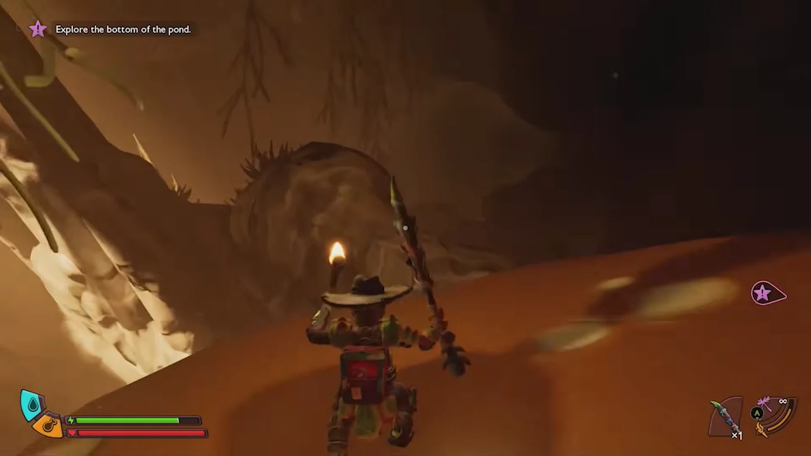 Player holding a lit torch inside a dim cavern while climbing toward the upper exit