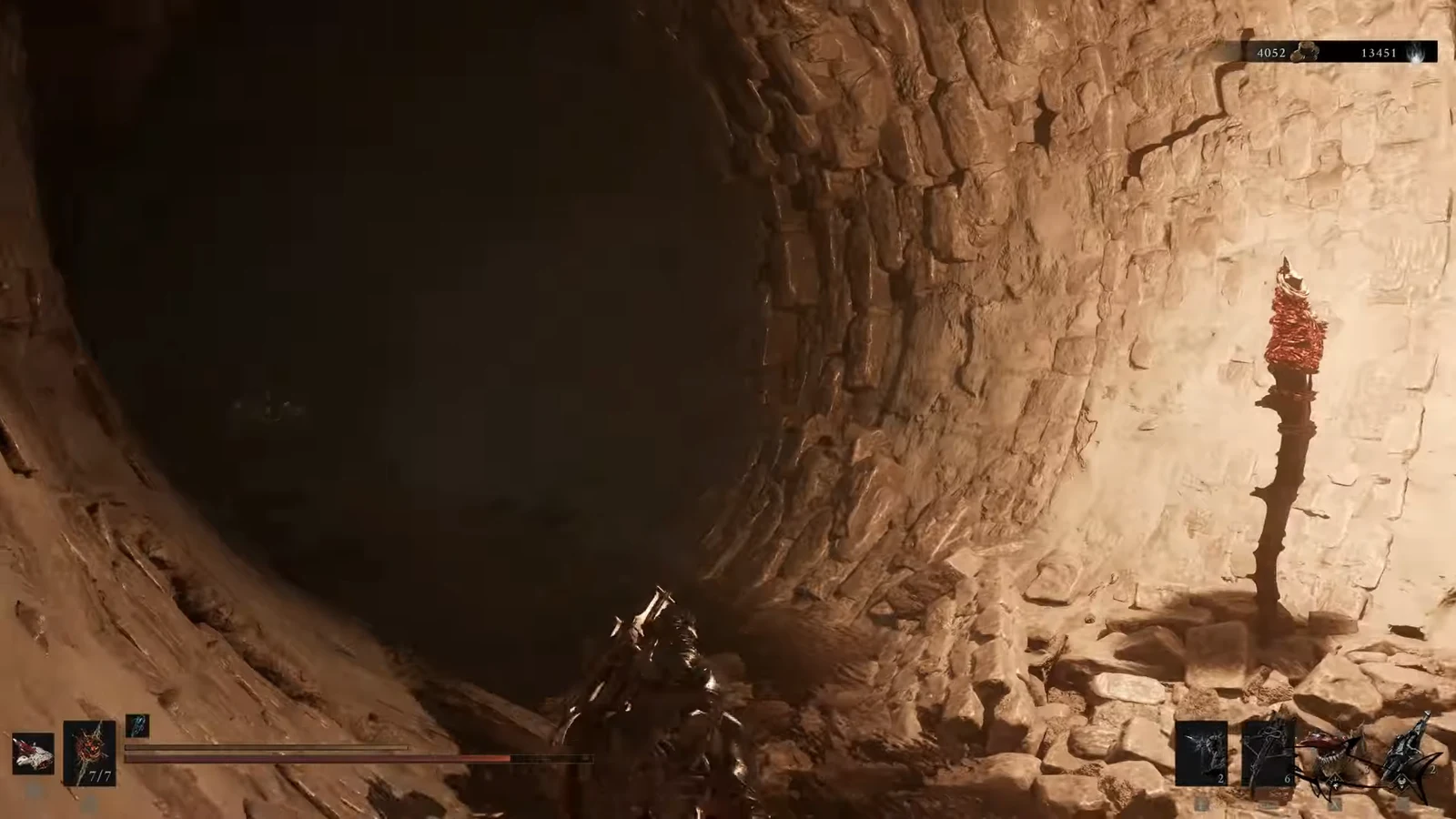 Player approaching a red-flamed torch mounted on the rock wall of a narrow tunnel