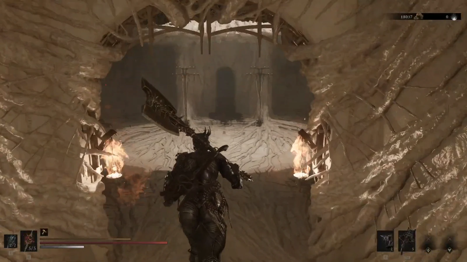 Armored warrior with a greatsword walking a torchlit cave toward a dark doorway.