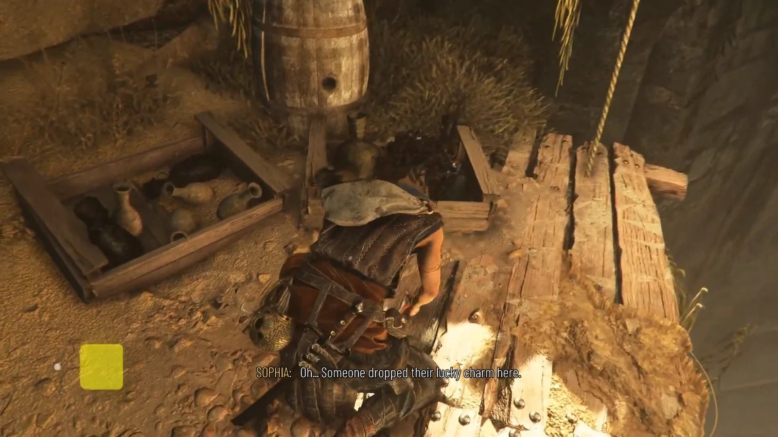 Sophia crouching to pick up the Polished Cornicello from a pottery crate on a wooden platform