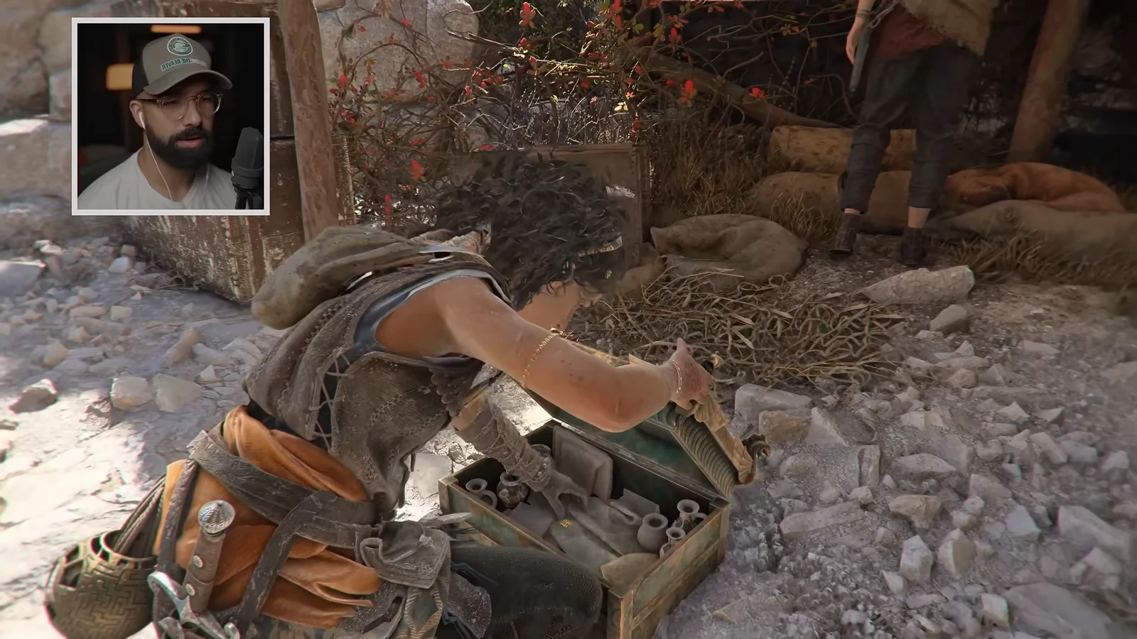 Sophia opens a green supply crate of equipment while a companion stands nearby