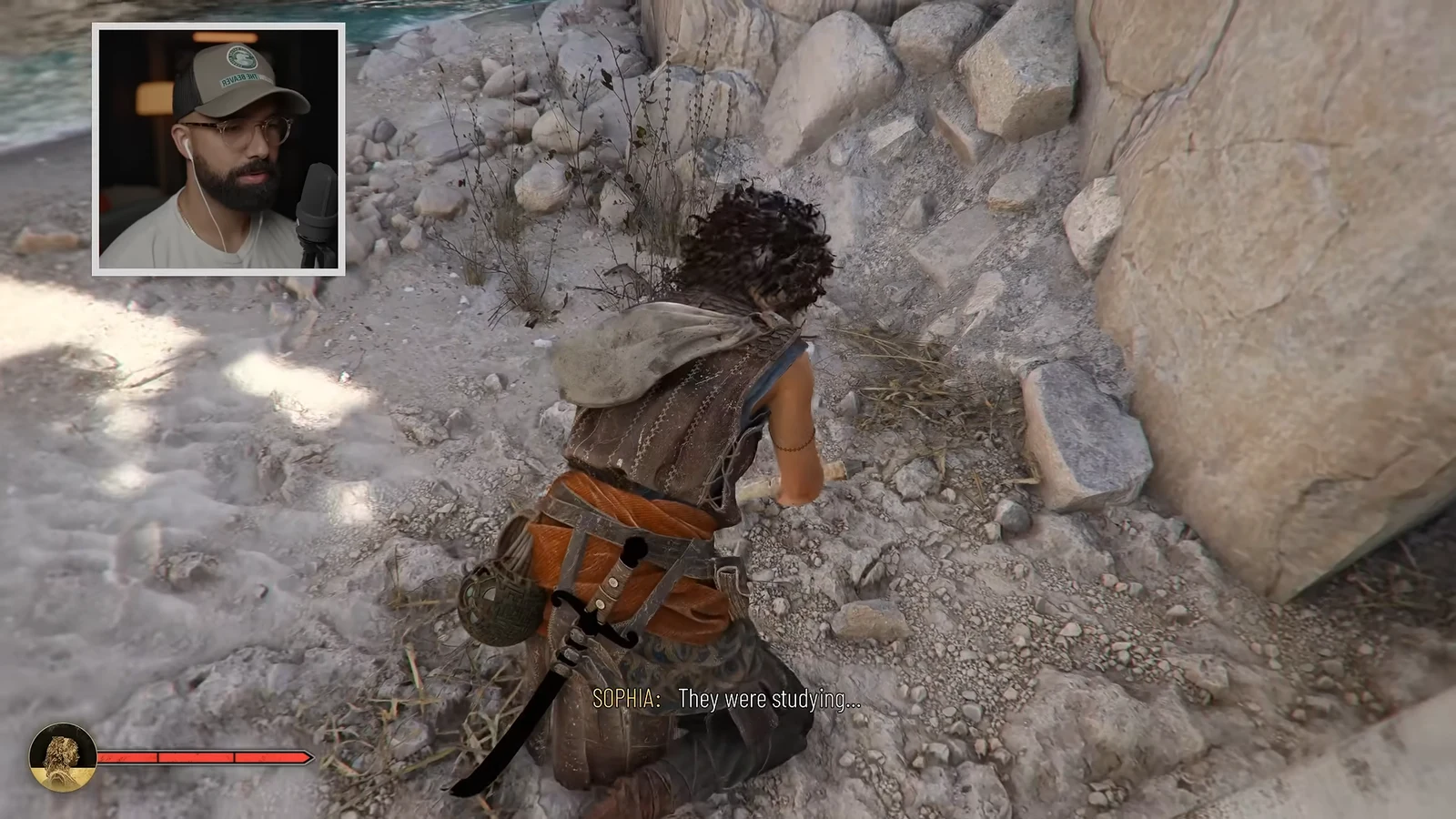Sophia crouches beside rocky terrain as a dialogue subtitle appears on screen