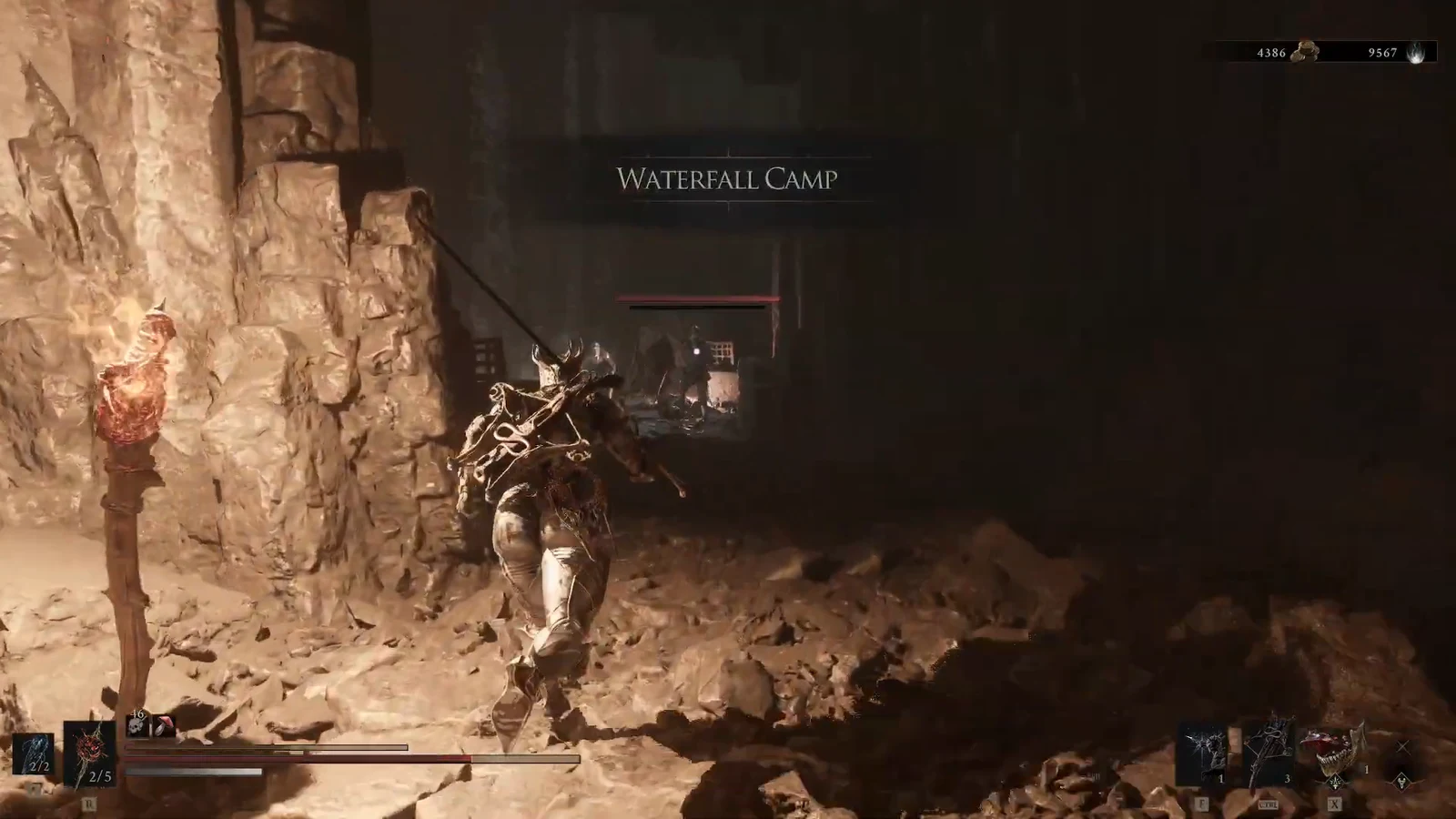 Waterfall Camp title on screen as an armored character walks through a cave toward an enemy