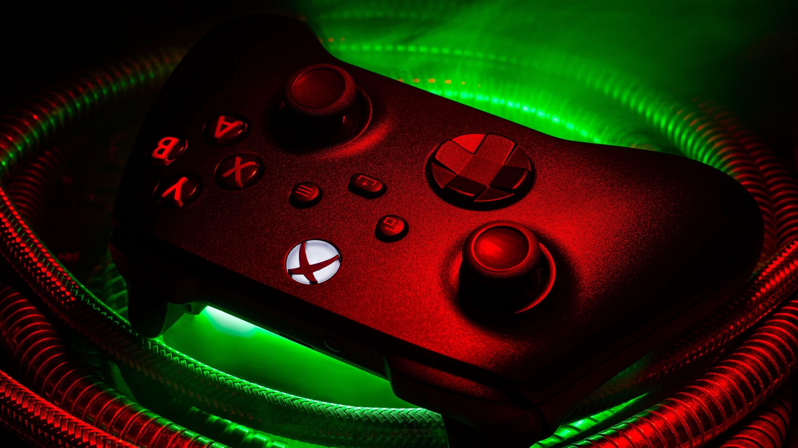 Xbox controller lit in red and green light, showing the thumbsticks and D-pad up close