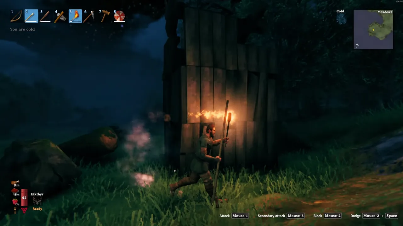 Torch equipped in the hotbar as the character moves through a dark forest
