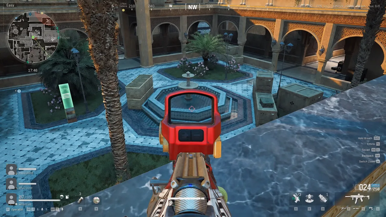 First-person view down the red rifle optic while scanning the courtyard from above