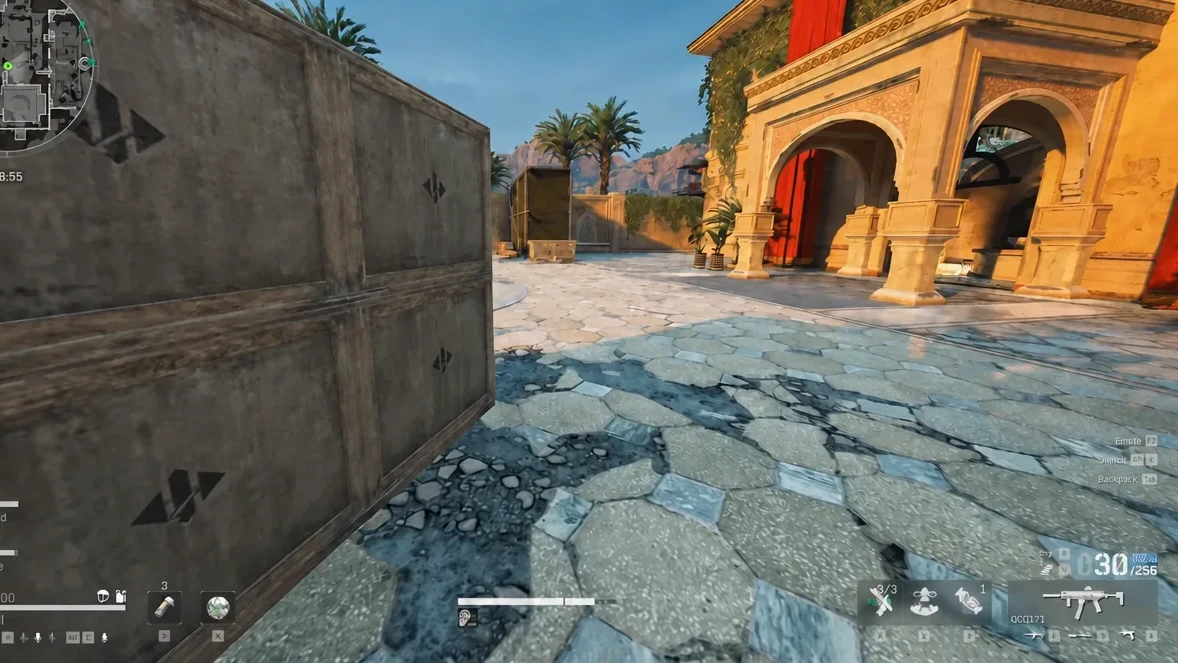 Player advances rifle-first across a tiled courtyard past stacked crates toward the pool area