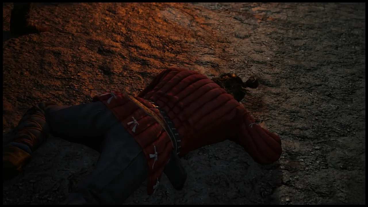 A defeated red-clad soldier lying face-down on rocky ground near the cabin