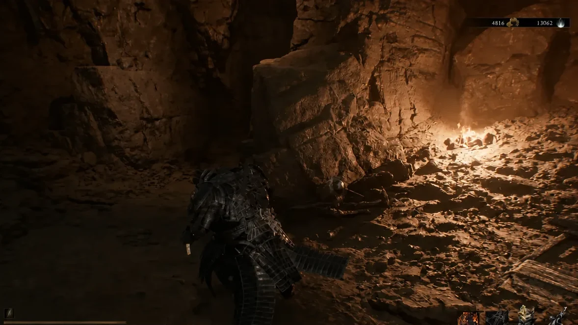 Player moving through a torchlit cavern toward a dark slumped figure on the way out of the mine