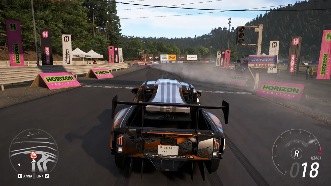 Racing HUD showing reverse gear as the car backs down the festival track at 18 km/h