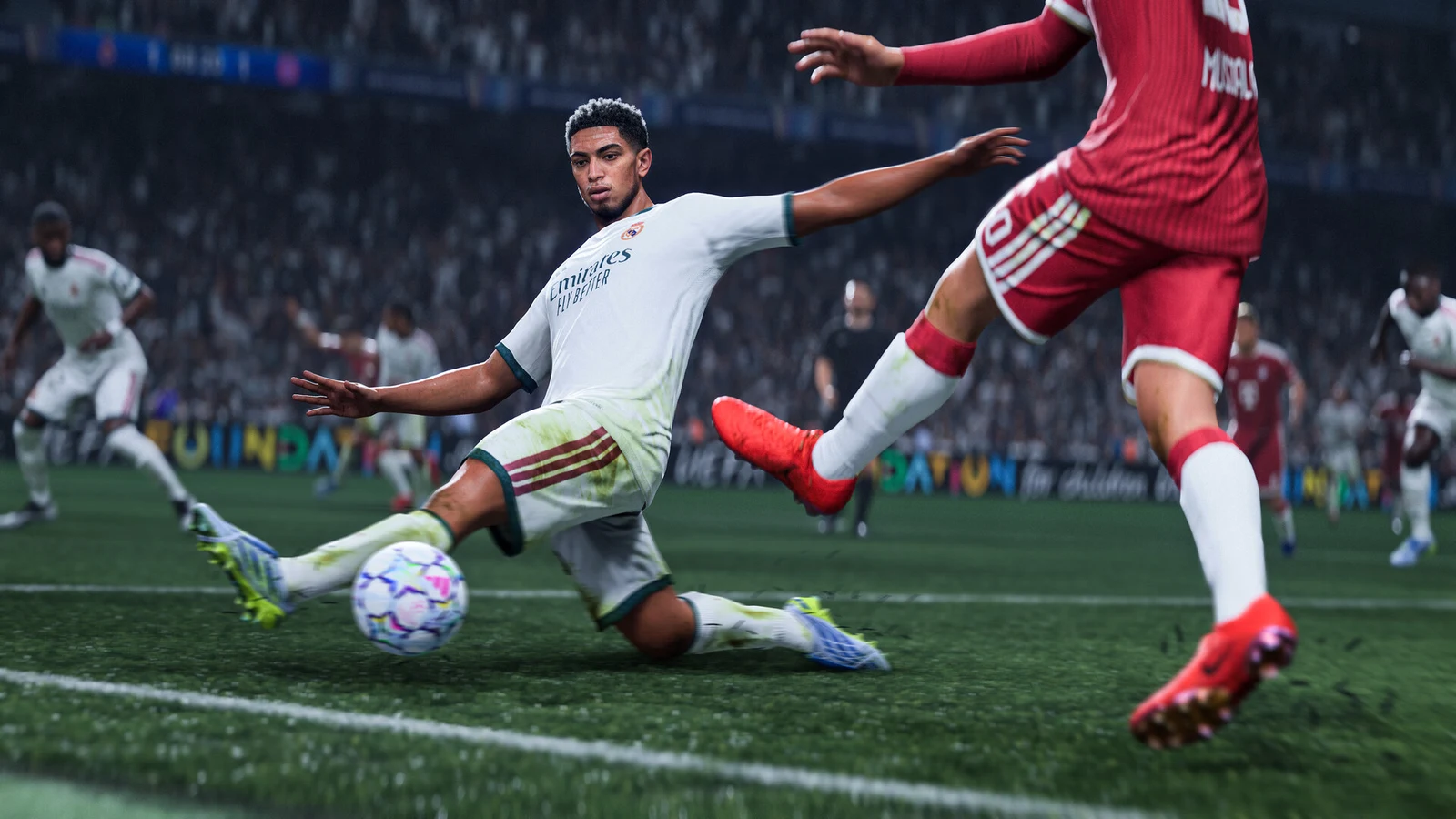 A white-shirted defender slides to challenge a red-shirted attacker for the ball on a stadium pitch.