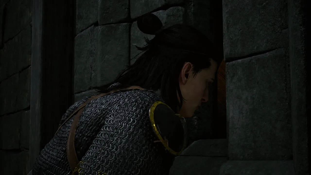 Coen leaning into a narrow opening in a stone wall to speak with barricaded soldiers