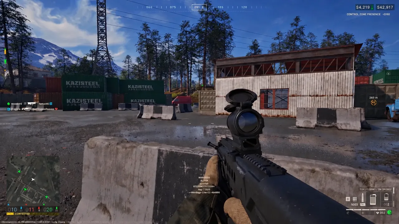 Optic aimed at a warehouse from behind a concrete wall, using cover to break line of sight
