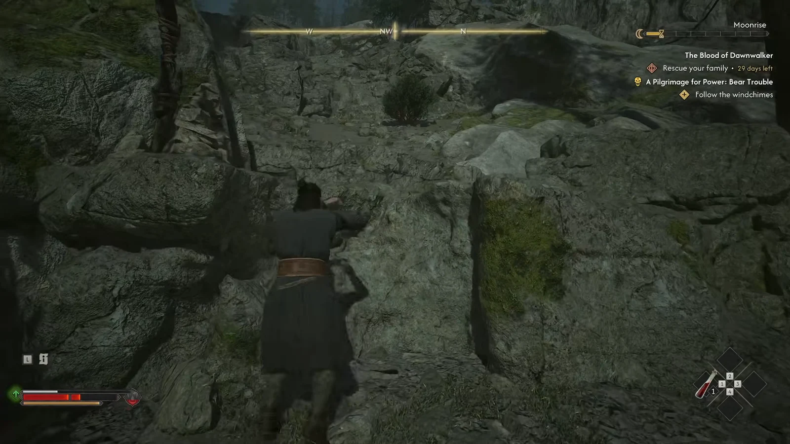 Coen pulling himself onto a high rocky ledge marked by a flagged windchime post
