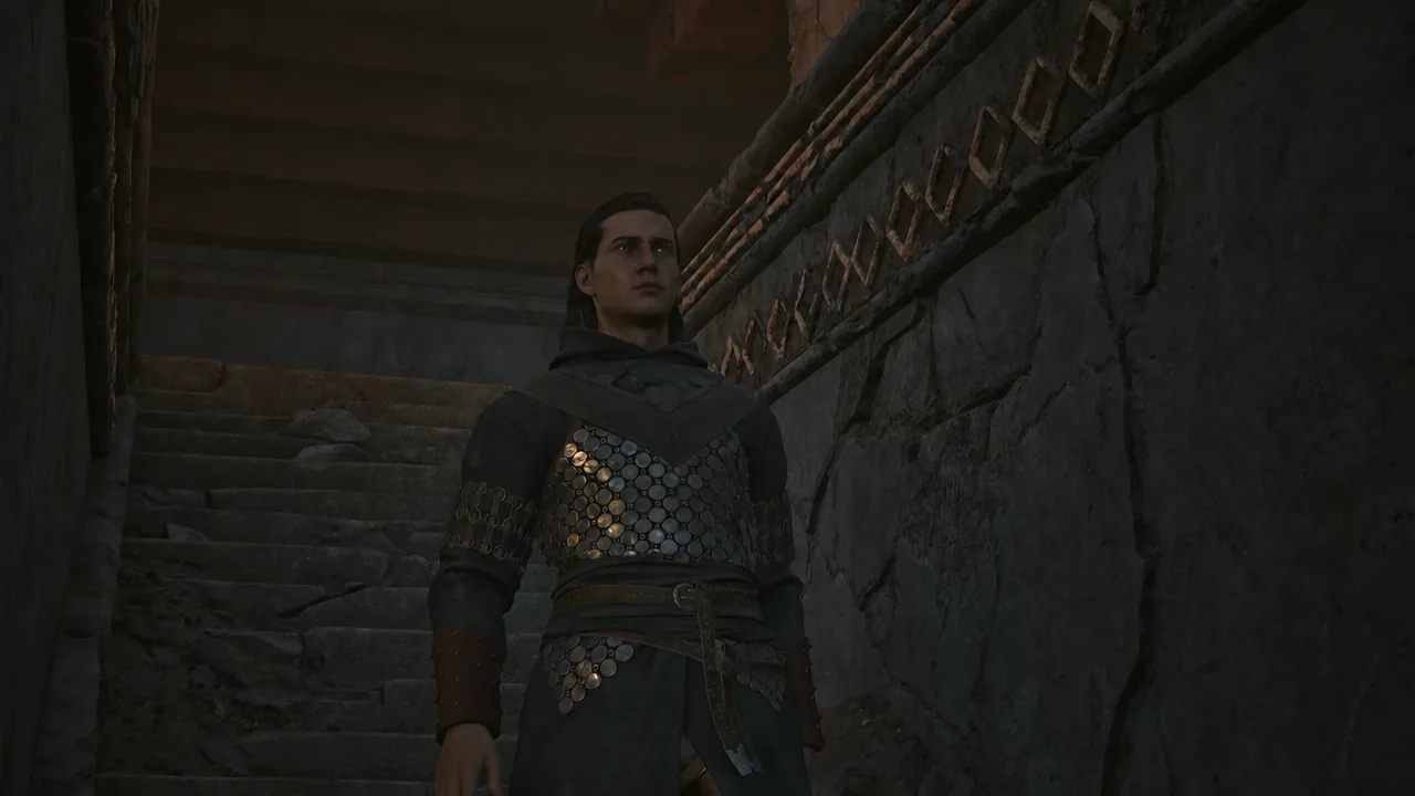 Coen in chainmail armor standing on a dim stone stairway inside the ruins