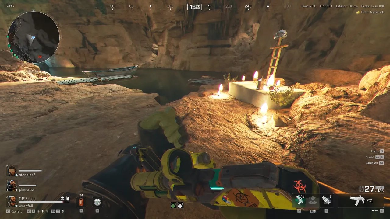 Player aiming a rifle at a candle-lit shrine next to an underground pool inside the cavern
