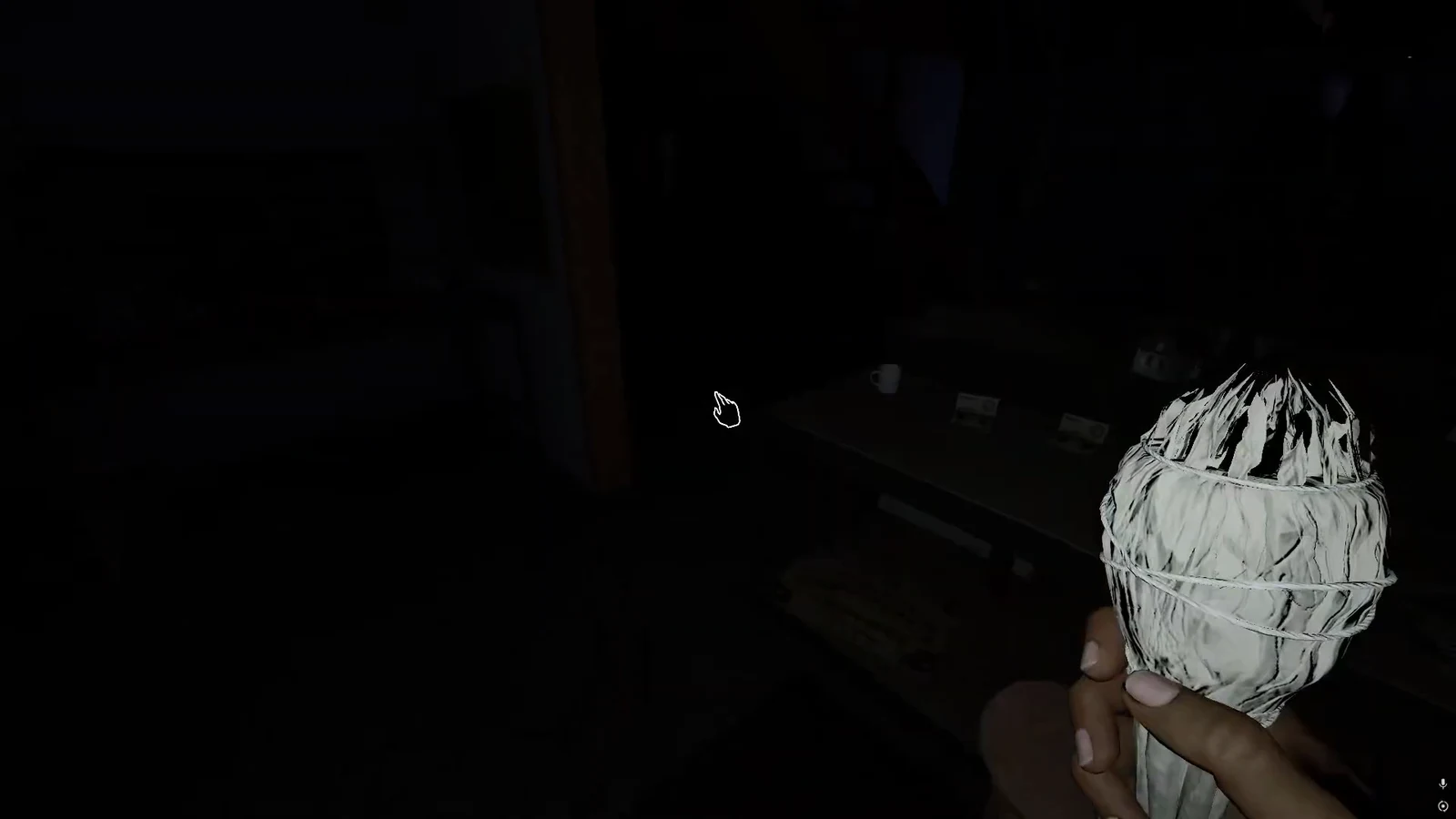 First-person view of a player carrying an item while the hand cursor highlights an object on a table
