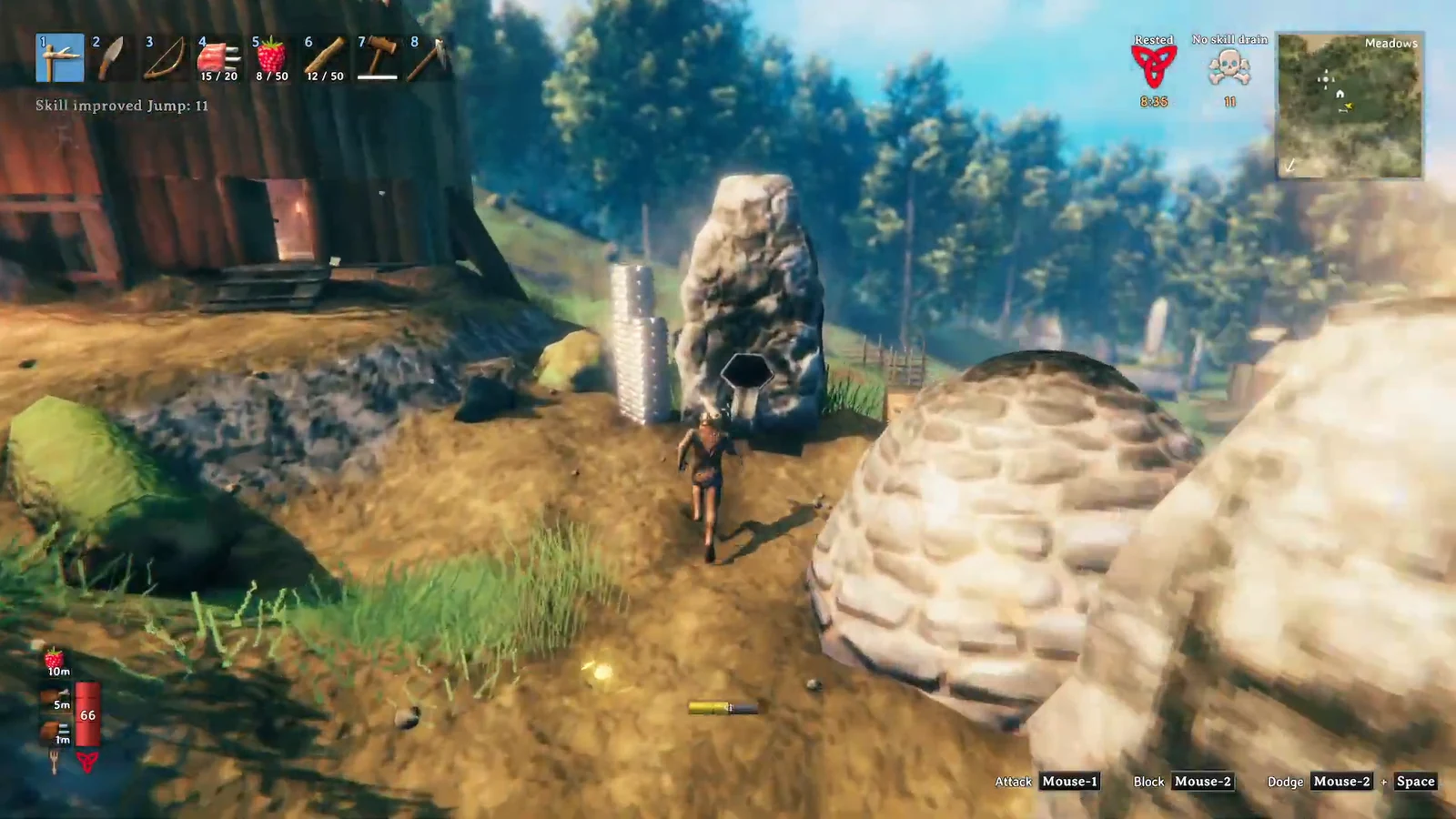 Valheim player holding a shield while walking up to a large rocky deposit outdoors