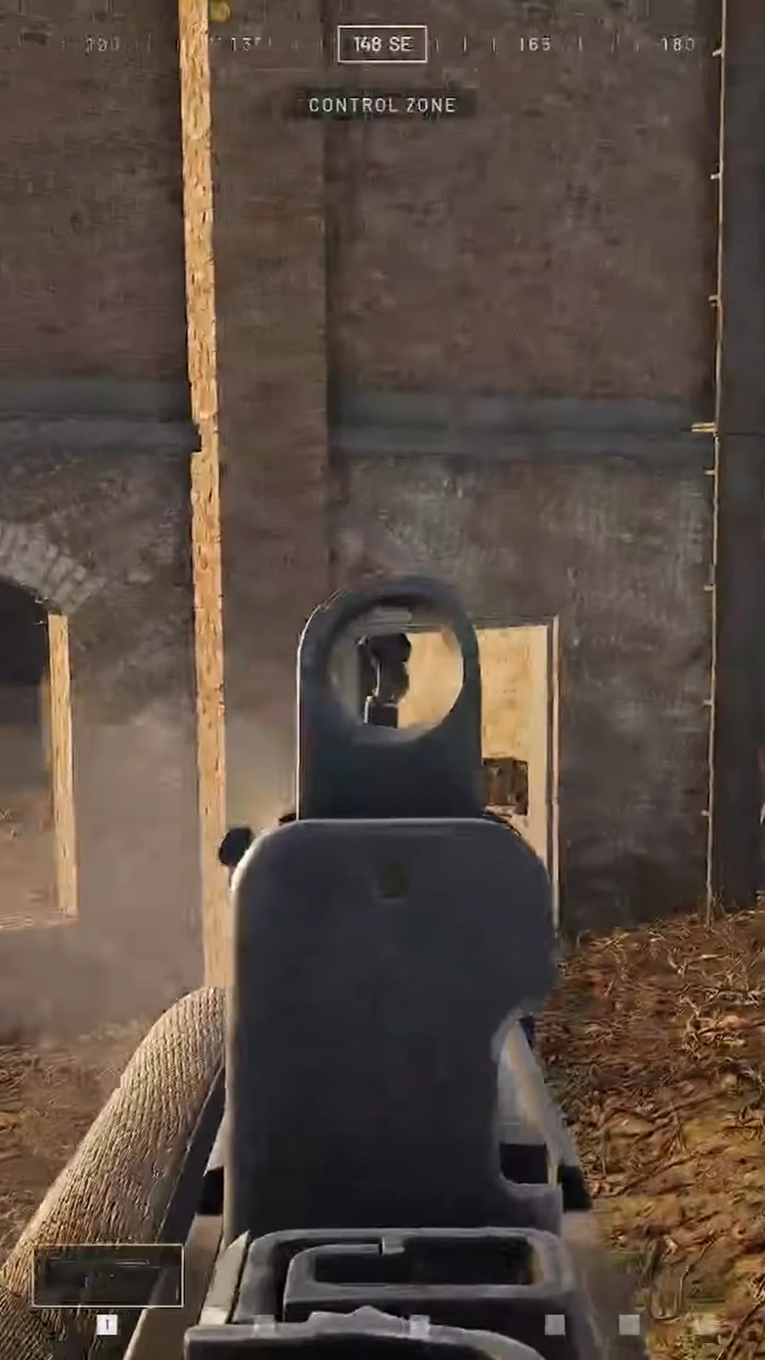 Aiming down iron sights at a doorway inside a building, with the Control Zone objective on the HUD