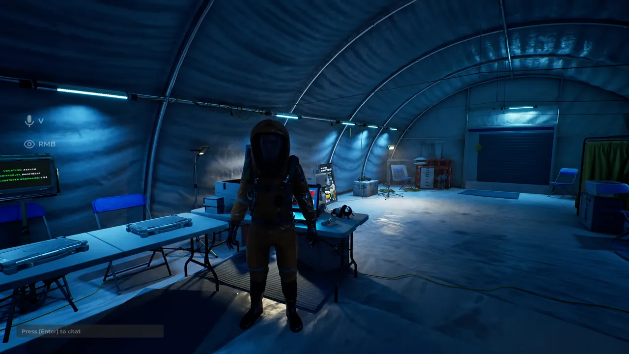 Crew member in an orange hazmat suit standing inside the blue-lit lobby tent before a run