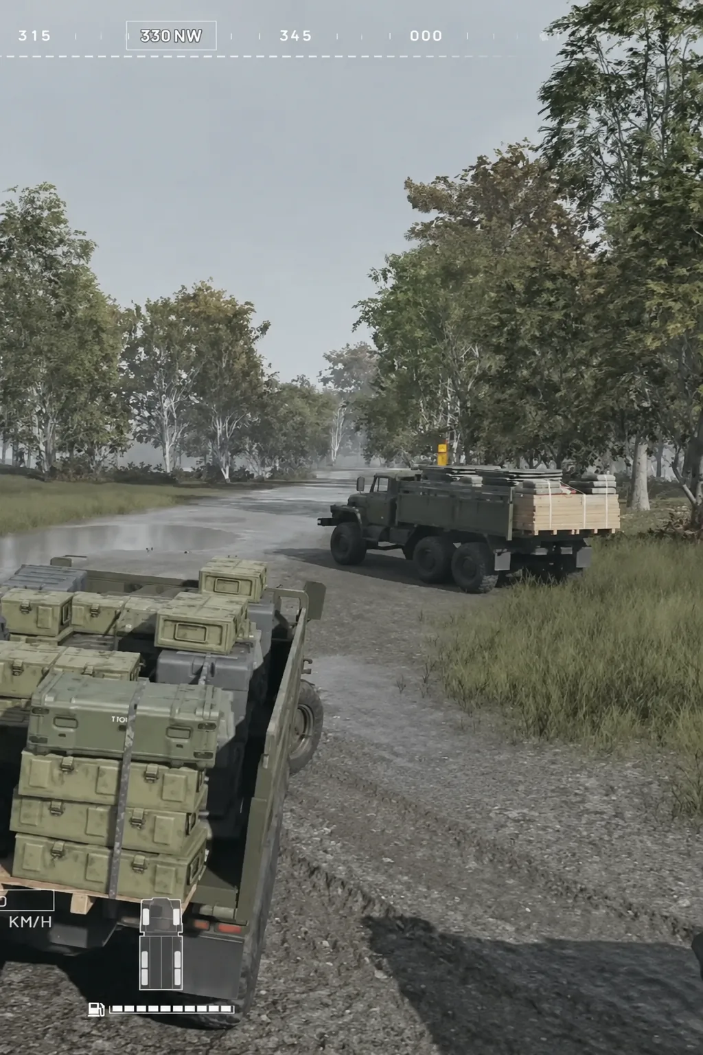 Player truck trailing a loaded cargo truck on a wooded road with the compass reading 330 NW