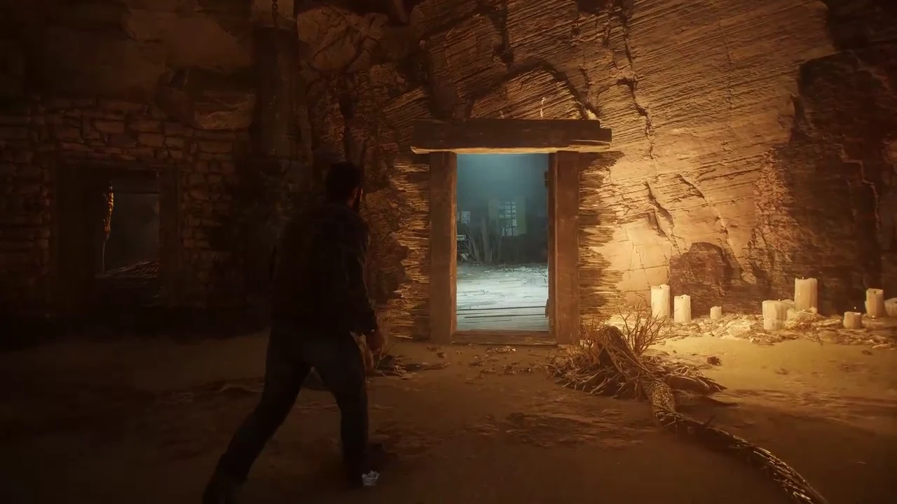 Logan walks from the candlelit stone chamber toward the open doorway into the wooden cabin
