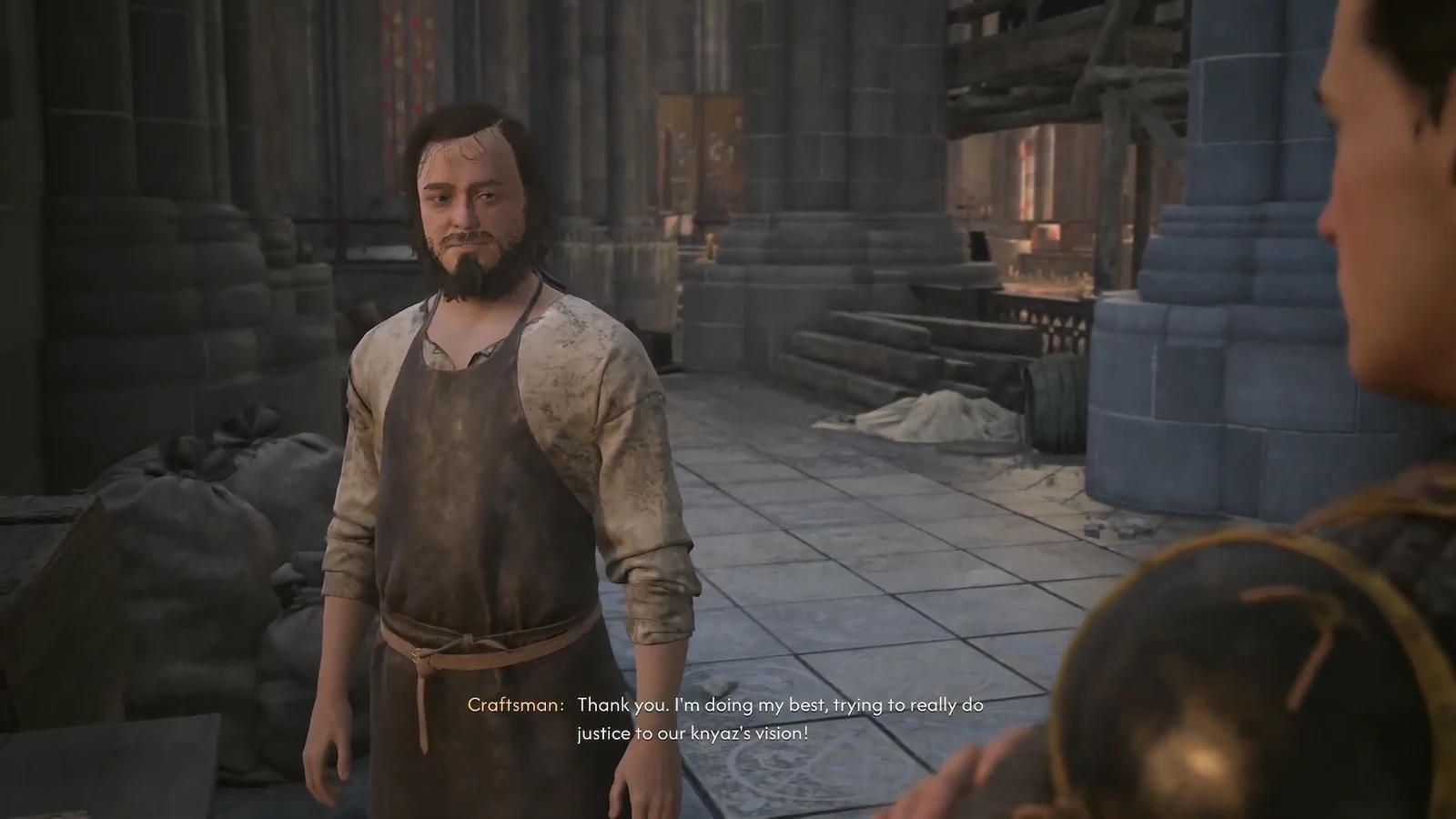 Coen speaking with the Craftsman in a stone courtyard during the cathedral conversation