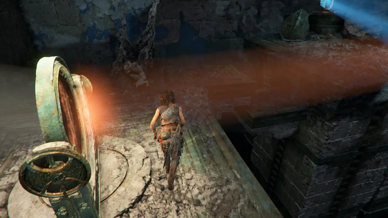 Sophia climbing towards a large mechanical wheel on a ruined stone platform inside the temple