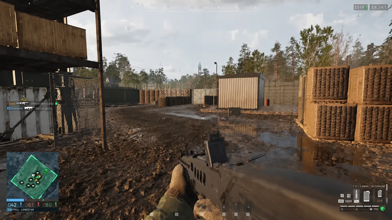 First-person view advancing with an assault rifle through a muddy industrial compound