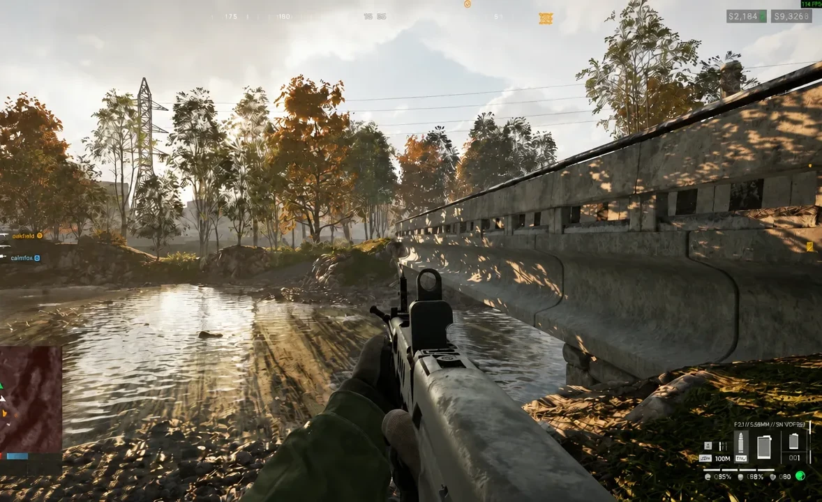 Player advancing through shallow water with an assault rifle raised beside a concrete structure