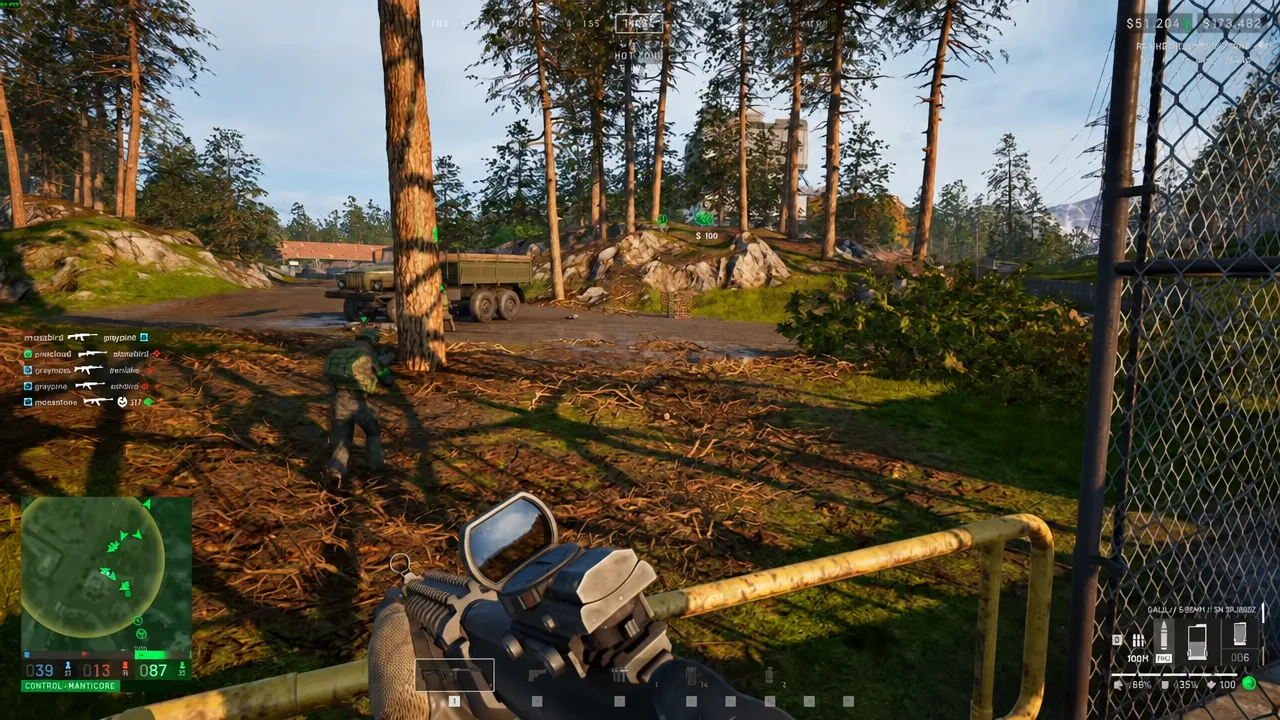 Rifle aimed through a wire fence toward a forested compound before pushing in