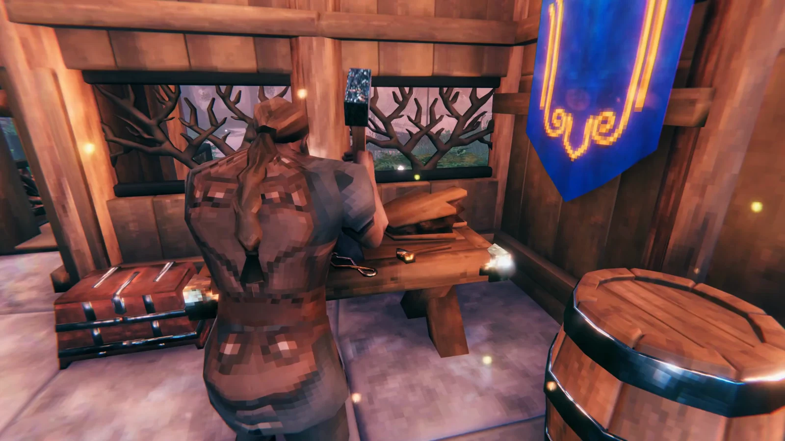 A Viking character works at a crafting station inside a decorated wooden hall beside a chest and barrel.