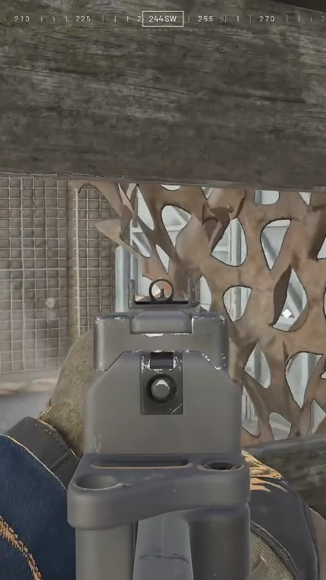 Aiming through iron sights out of a bunker observation port toward a metal barrier