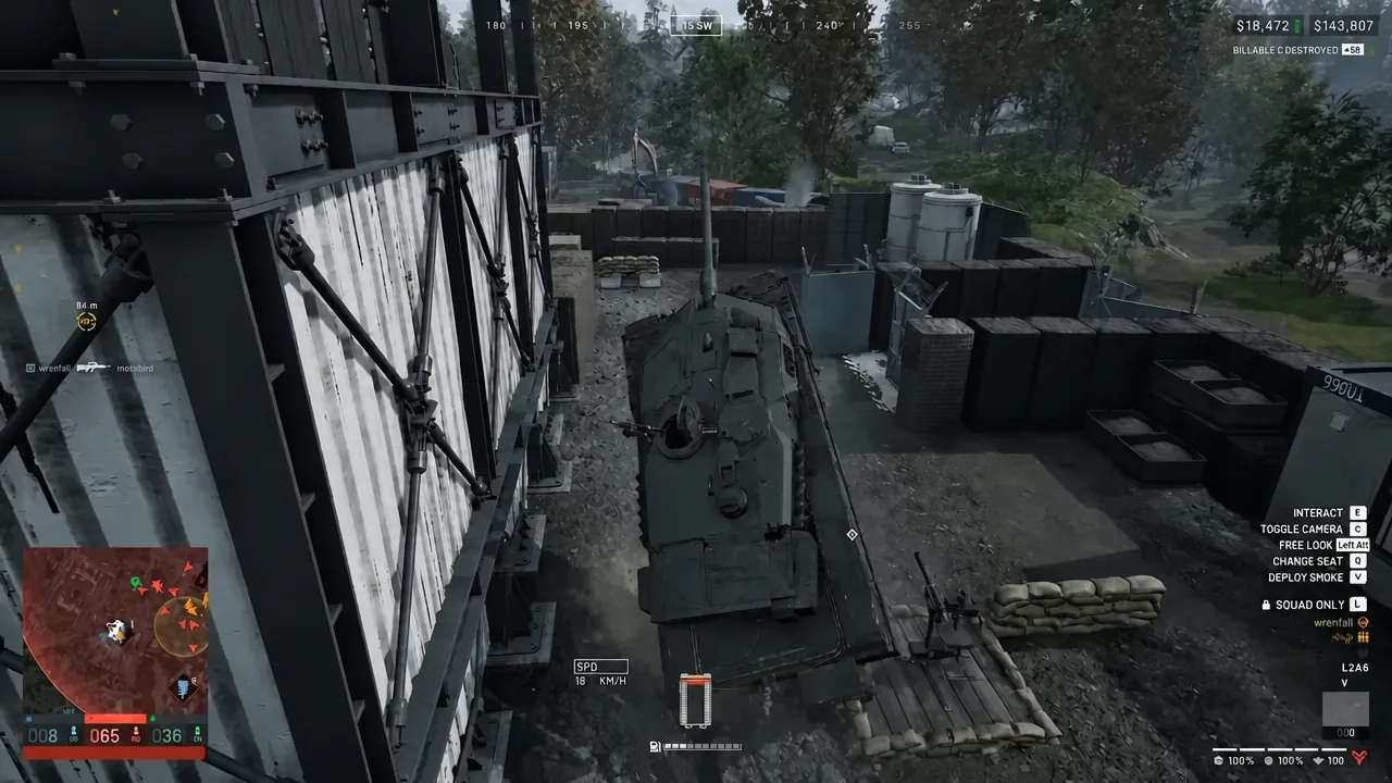 Player driving an armored vehicle past a building in WARDOGS with the Interact prompt on screen