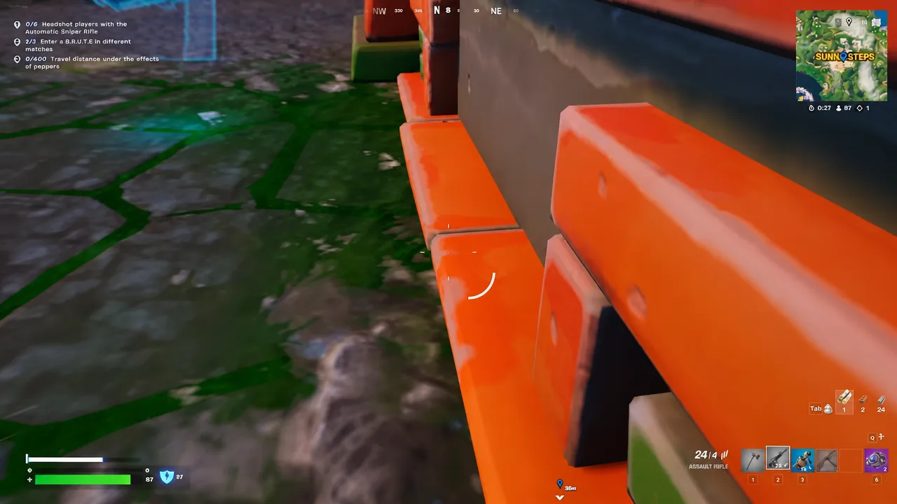 Player holding an assault rifle behind orange cover in a Fortnite firefight