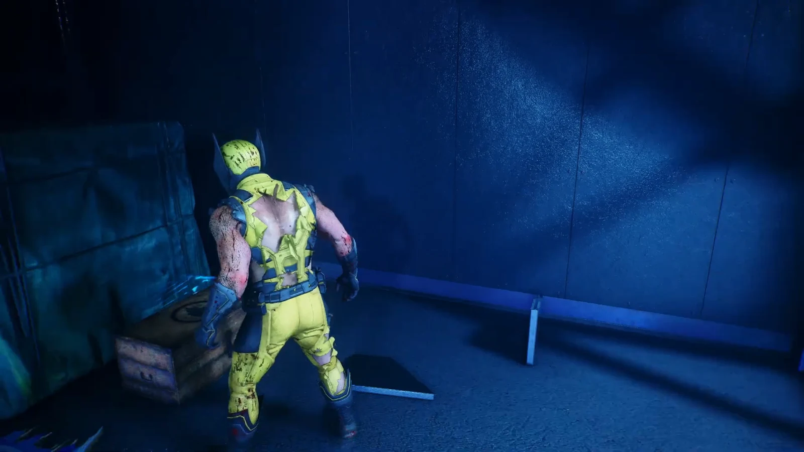 Logan stands next to an opened supply crate in a blue-lit basement corridor