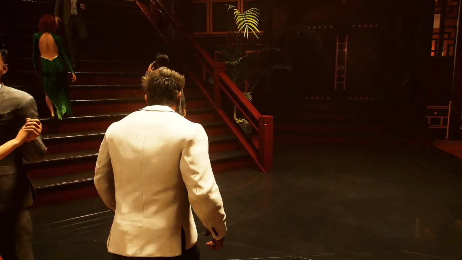 Logan in a white suit walks toward the staircase inside the dim casino floor