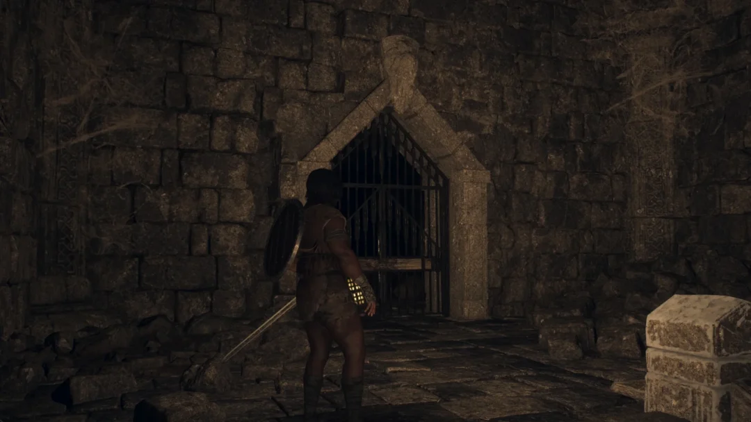 The Arisen in front of a barred iron gate in a pointed-arch stone doorway in Dragon's Dogma 2: Dark Arisen