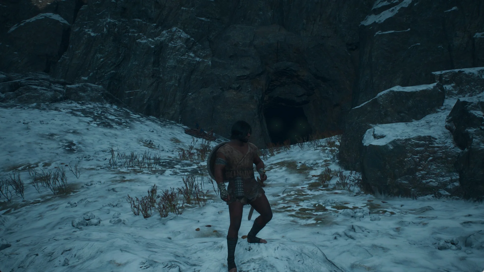 The Arisen on the snowy southern shore of Lake Norgan with a dark cave mouth in the rock right behind him