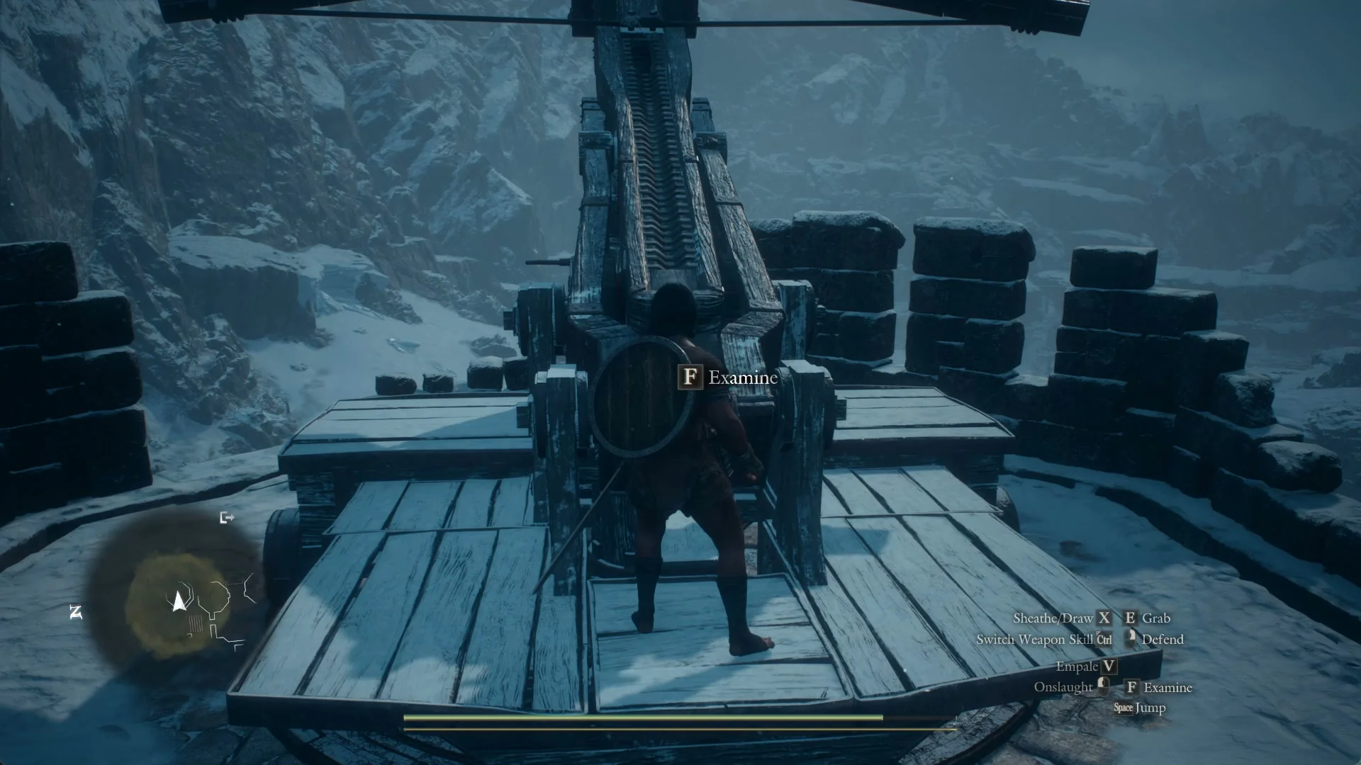 Examine prompt at the rear of the wooden ballista on its timber deck, with the snowy gorge beyond the battlements