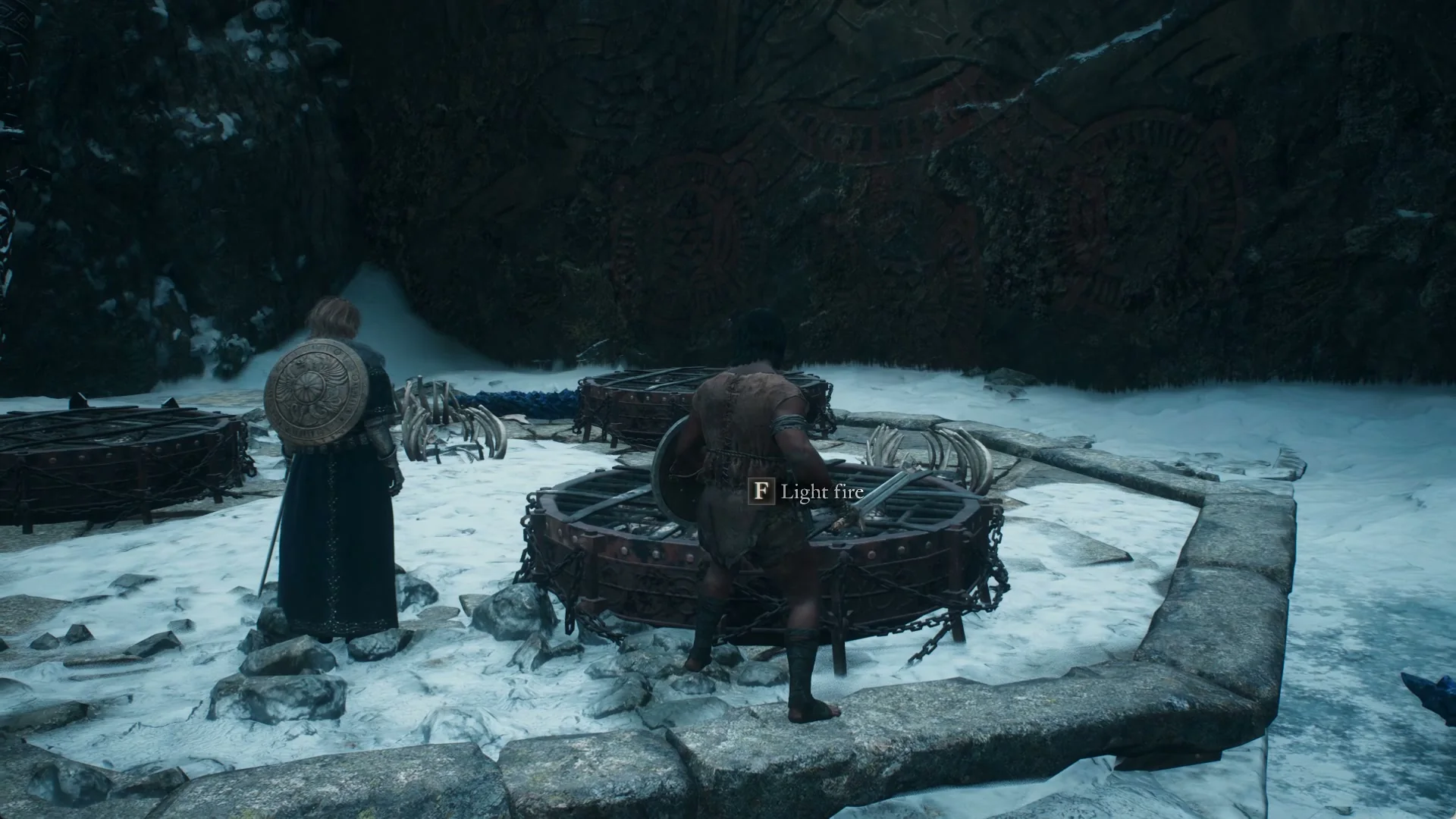 Light fire prompt on a round iron brazier, with two more braziers and rib bones on the stone platform and a red mural on the rock behind