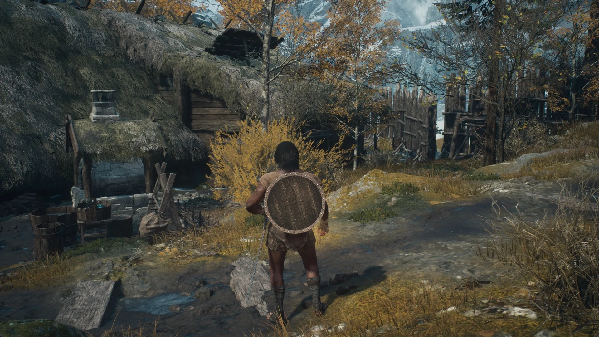 The Arisen with a round shield on the back walking past the forge hut in the Norgandian Settlement