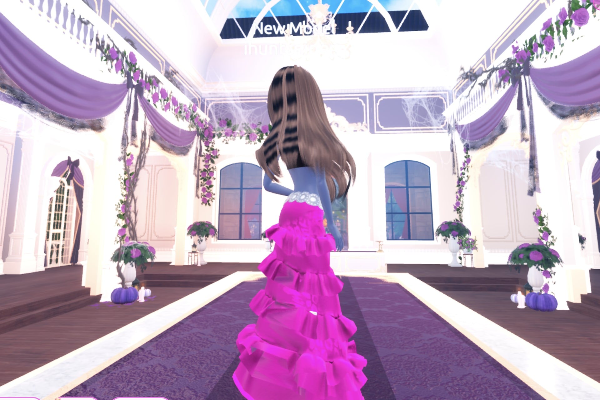 Back view of the pop-star glam look: long wavy hair over the hot-pink tiered gown with its silver belt